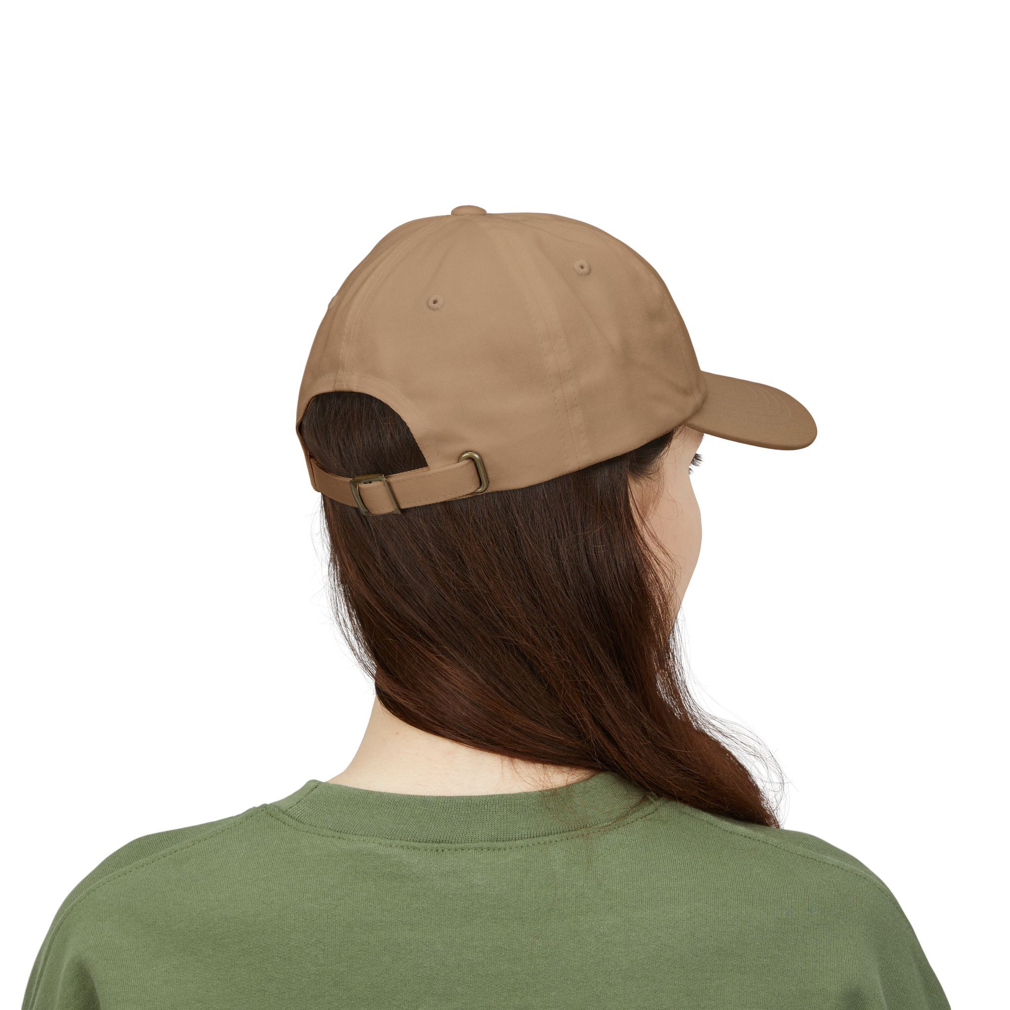 A person with long brown hair, wearing the Macrons Secret Weakness Baseball Cap and a green shirt, is shown from behind against a white background, evoking a quiet strength.