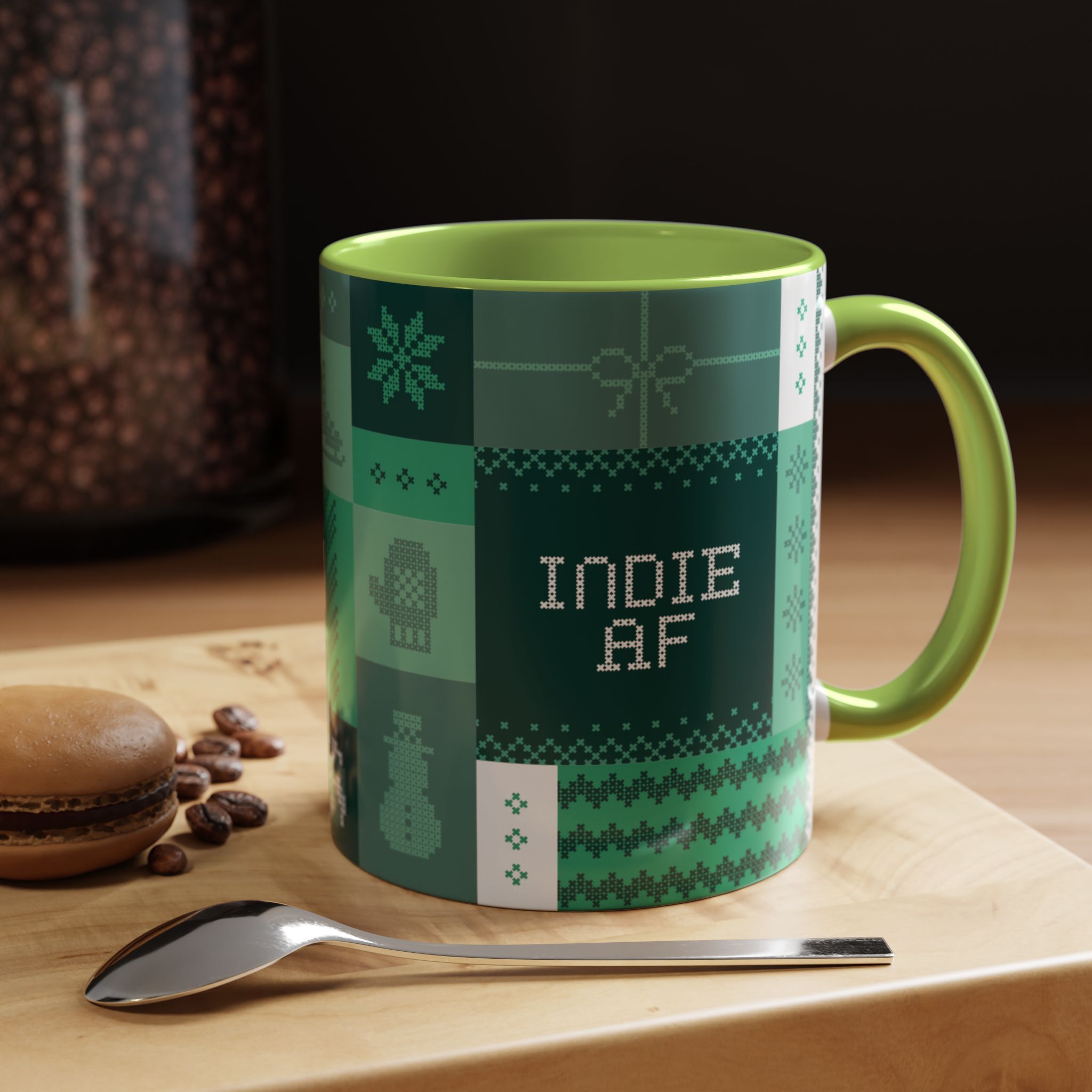 The "Mandatory Fun" Mug - Green | 11oz Indie AF 2025 Holidays by Grown features pixel art and sits on a wooden surface with a macaron, coffee beans, and a spoon—ideal for anyone embracing mandatory fun.