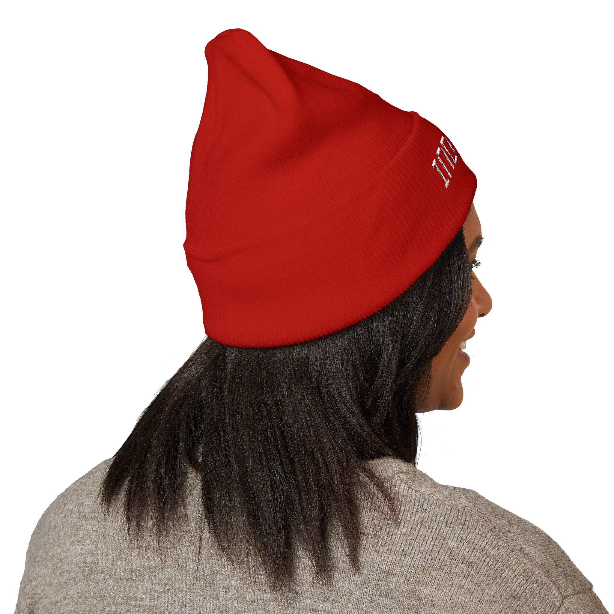 A person with straight dark hair wears The Deep Dive: Indie AF 2025 Holidays by Grown cuffed beanie with light embroidery, paired with a light brown sweater, facing away and glancing over their shoulder.