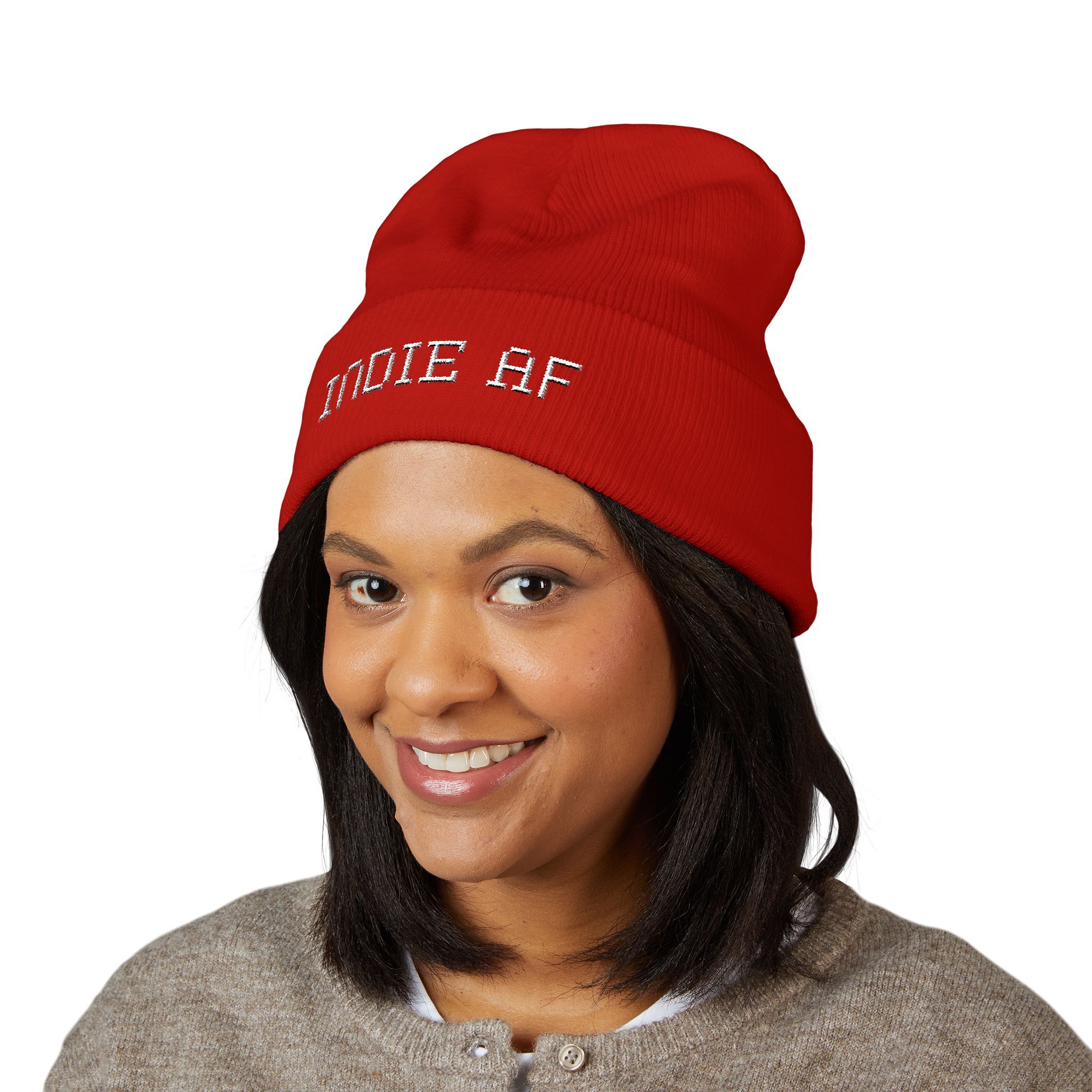 A woman with shoulder-length dark hair smiles at the camera against a white background, wearing The Deep Dive: Indie AF 2025 Holidays by Grown cuffed beanie with light embroidery and a gray button-up top.