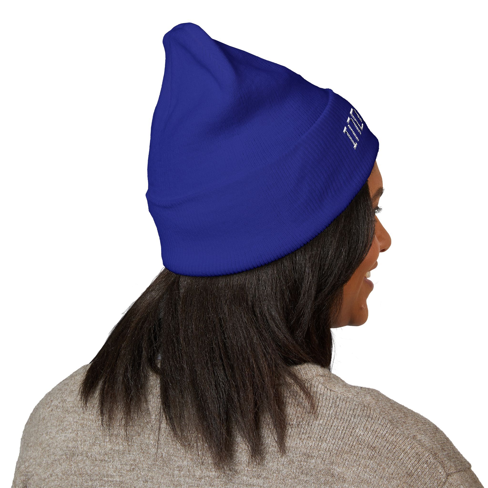 A person with shoulder-length dark hair wears The Deep Dive: Indie AF 2025 Holidays by Grown cuffed beanie in blue with light embroidery and a beige sweater, shown from behind and to the side—serving indie af vibes.