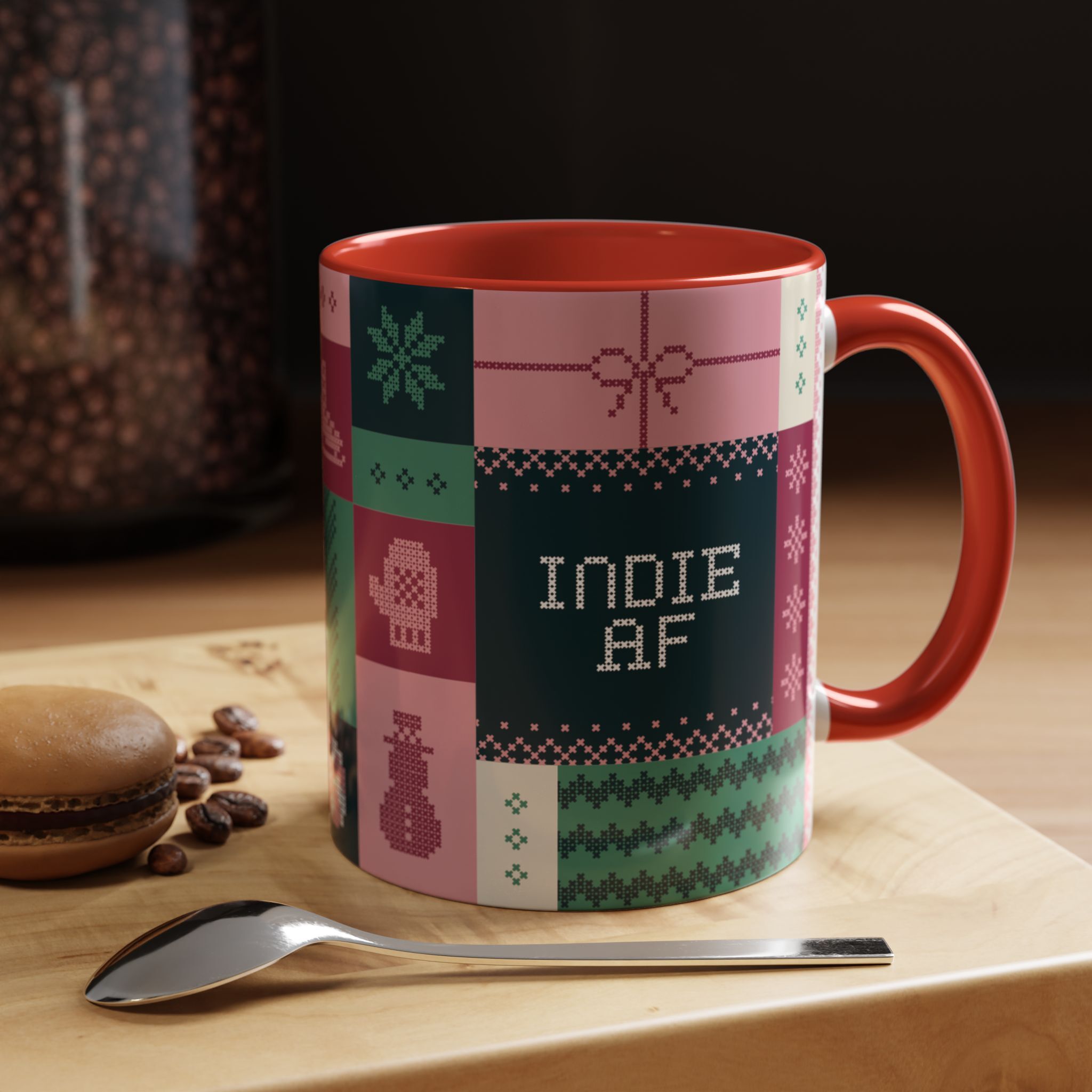 The "Mandatory Fun" Mug - Pink | 11oz Indie AF 2025 Holidays by Grown features pixel art and INDIE AF text, with a red handle—perfect for your coffee breaks. Placed on wood with a spoon, macaron, and coffee beans nearby.