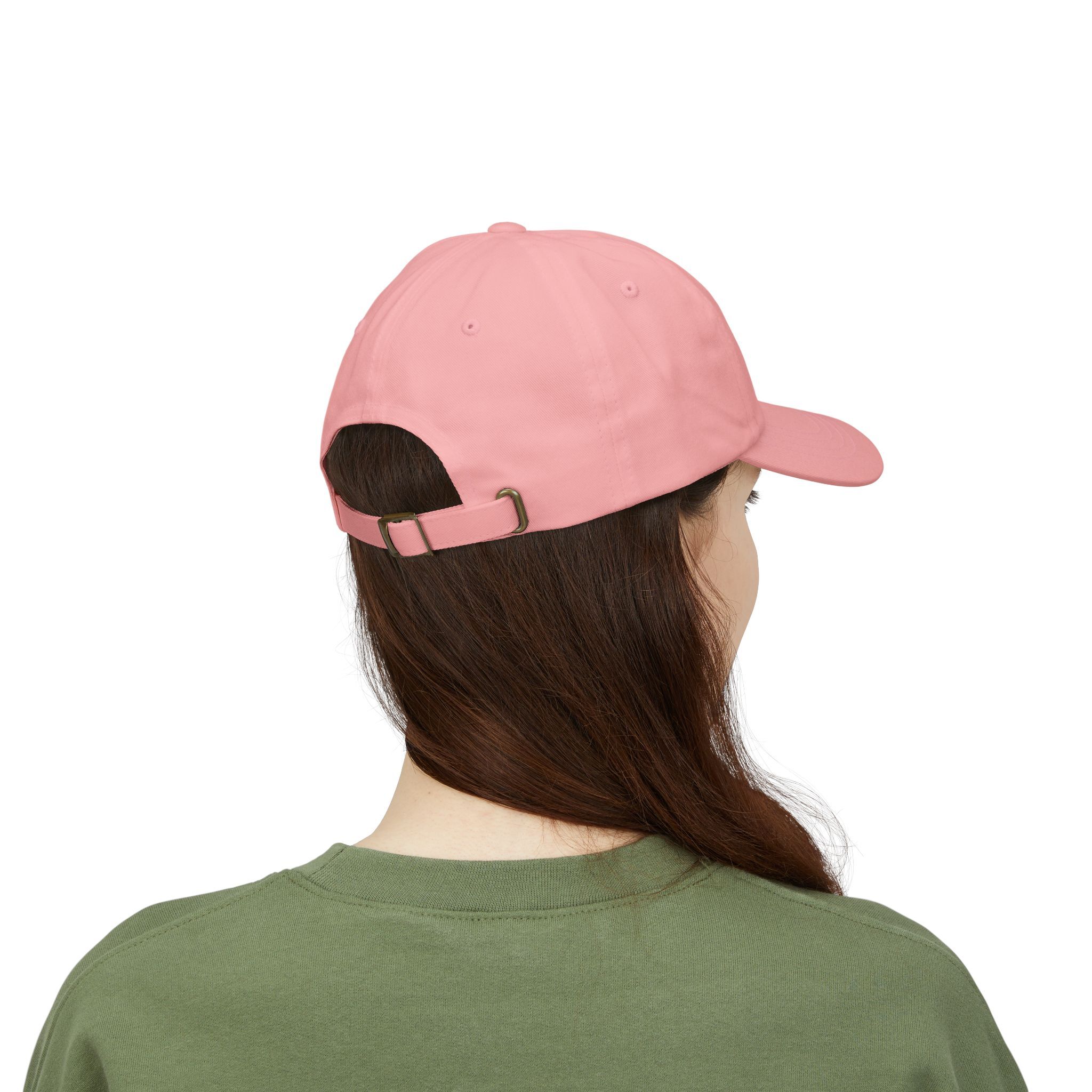 A person with long brown hair, shown from behind in a green shirt, wears The Macrons Secret Weakness Baseball Cap in pink, as if subtly concealing a hidden vulnerability.