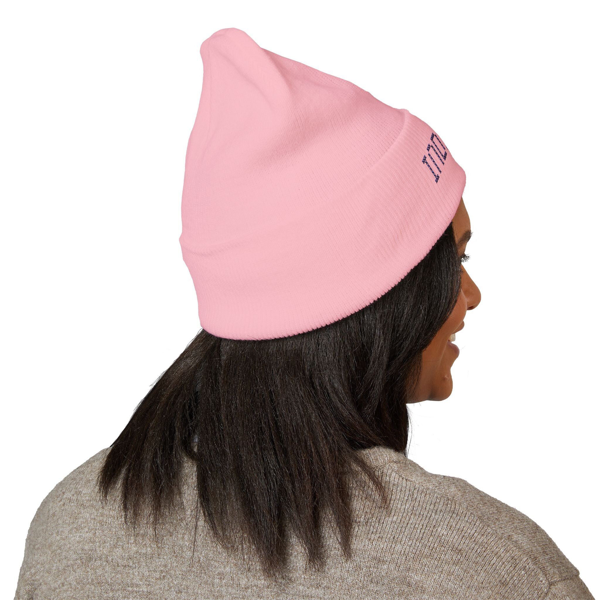 A person with straight dark hair wears the Indie AF 2025 Holidays by Grown: Cuffed Beanie | Dark Embroidery in light pink and a gray sweater, shown from behind and slightly in profile.