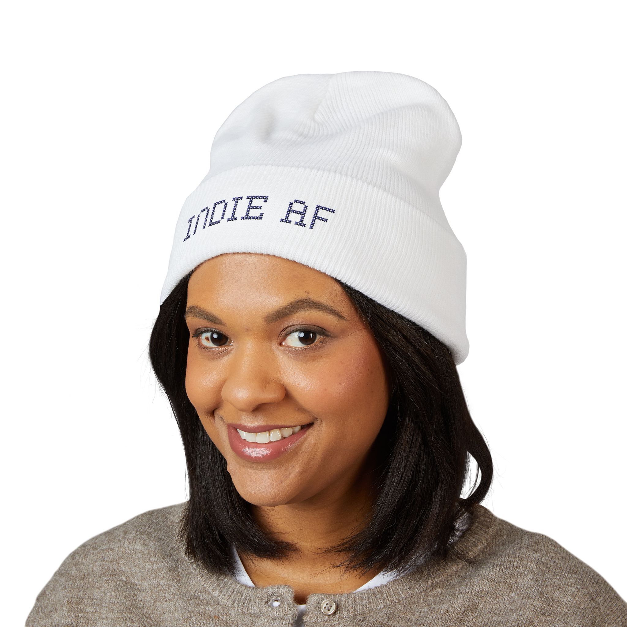 A woman smiles at the camera while wearing the Indie AF 2025 Holidays by Grown: Cuffed Beanie with dark embroidery, set against a plain white background.